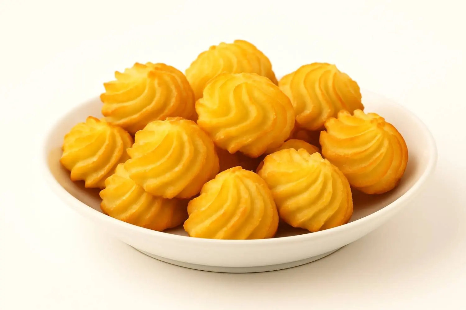 Papas Duchesse doradas servidas en un plato blanco sobre fondo claro.